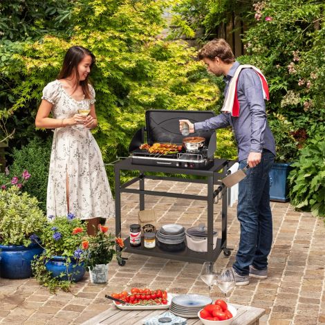 Välitingimustesse mõeldud grillkäru kahe riiuli, nelja lukustatava ratta ja külgkäepidemega, must